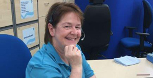 An NHS 24 staff member sitting at a desk wearing a telephone headset